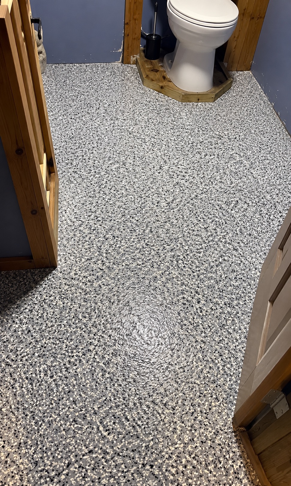 The same bathroom after coating: seamless gray, white and black flake floor up to the toilet platform