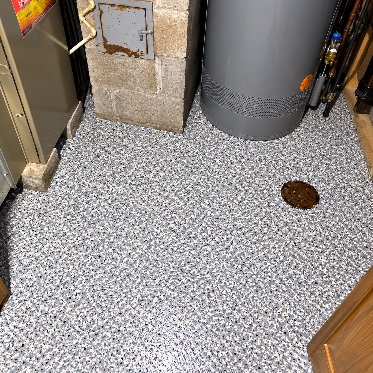 The same utility room finished: gray, white and black flake floor around the furnace, water heater and floor drain