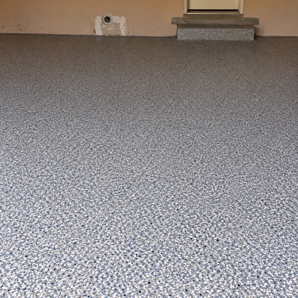 The same garage after coating: gray, white and black flake floor with the entry step coated to match