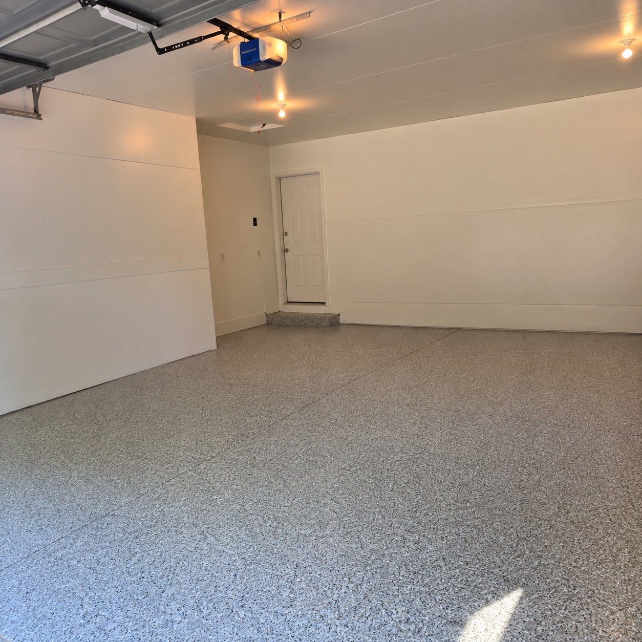 The same garage after coating: gray flake floor across the full slab with the door step coated to match
