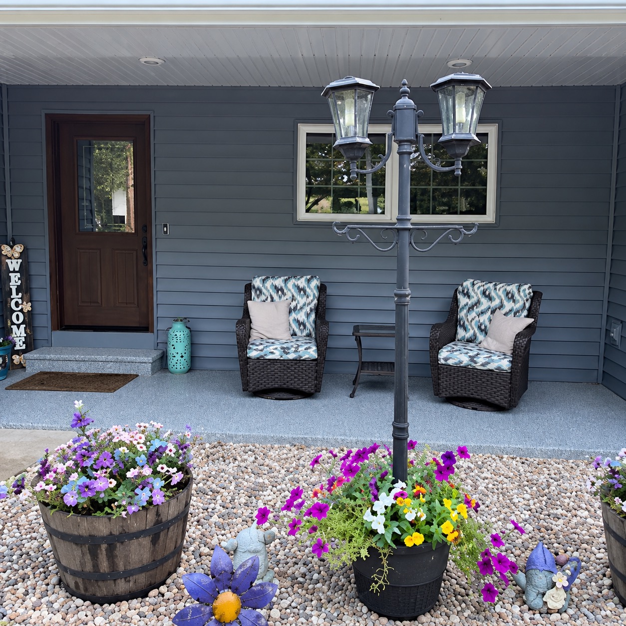 Front porch with a light gray flake coating, flower barrels and a lamp post